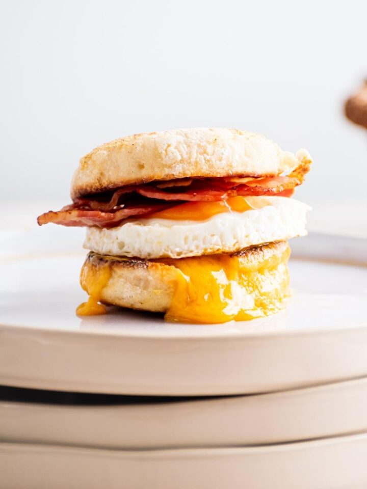 An egg mcmuffin on a stack of three plates.