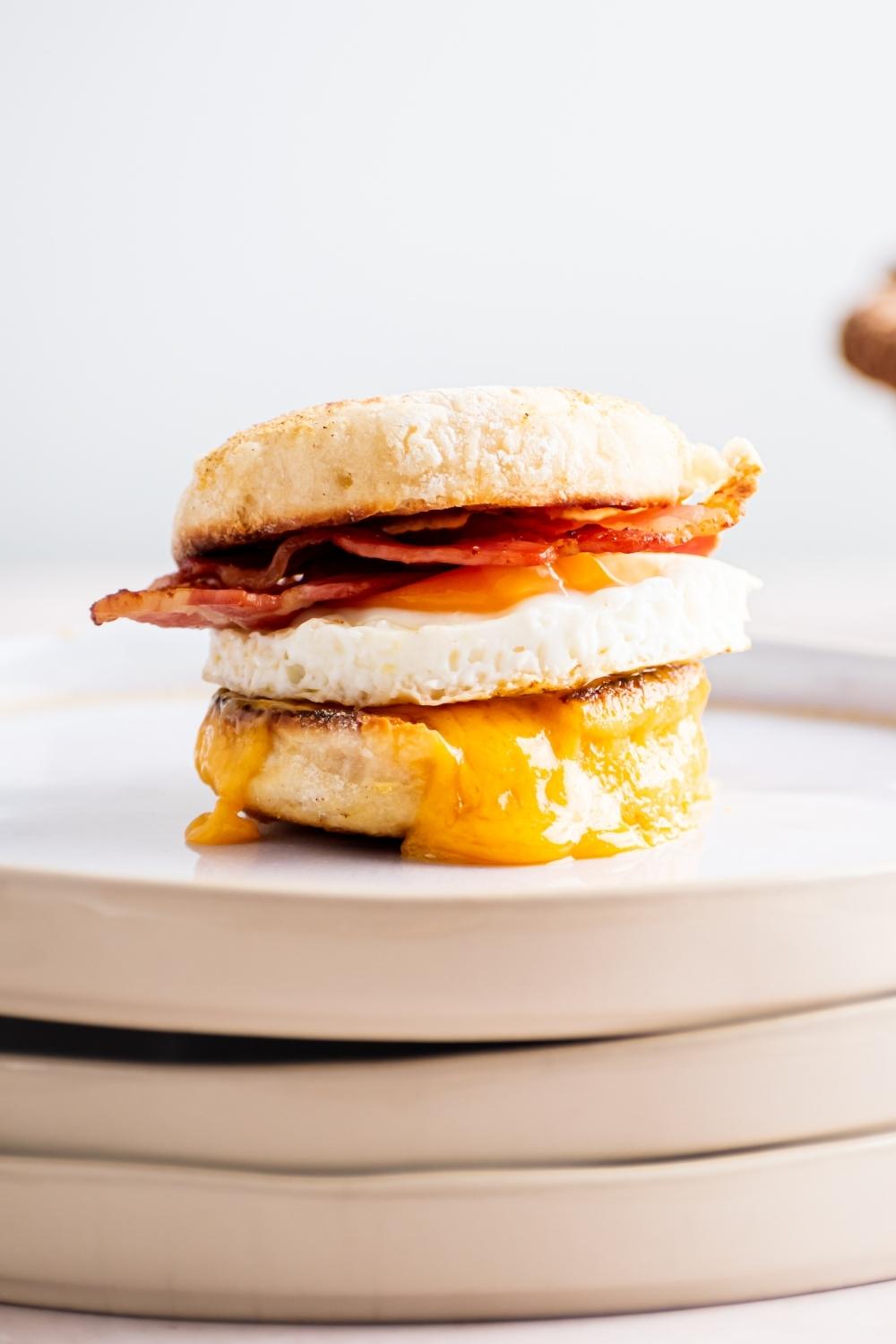 An egg mcmuffin on a stack of three plates.