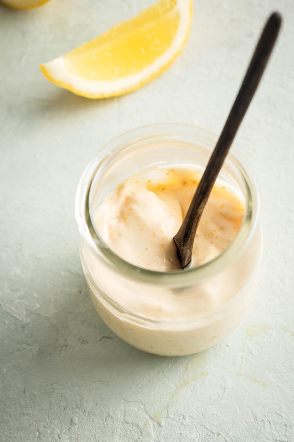 Chipotle mayo with a wooden spoon in it in a glass jar.