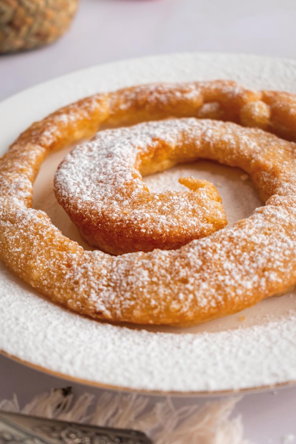 Part of a funnel cake on a white plate.