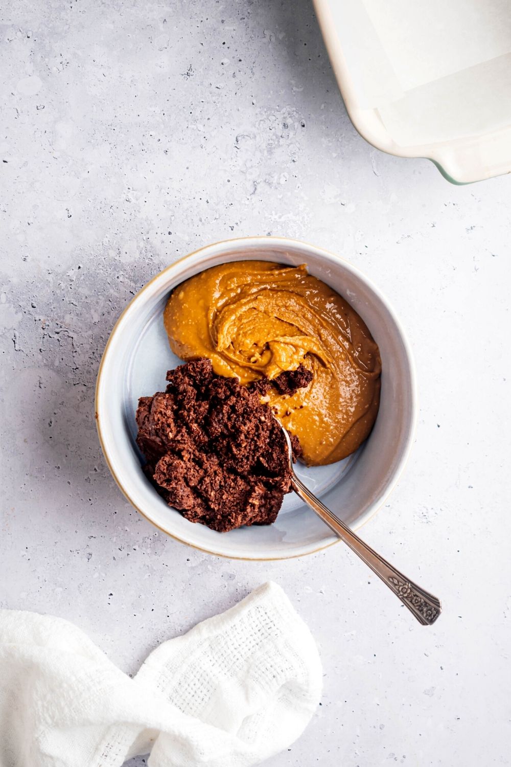 A bowl that is filled half with chocolate frosting and half with peanut butter.