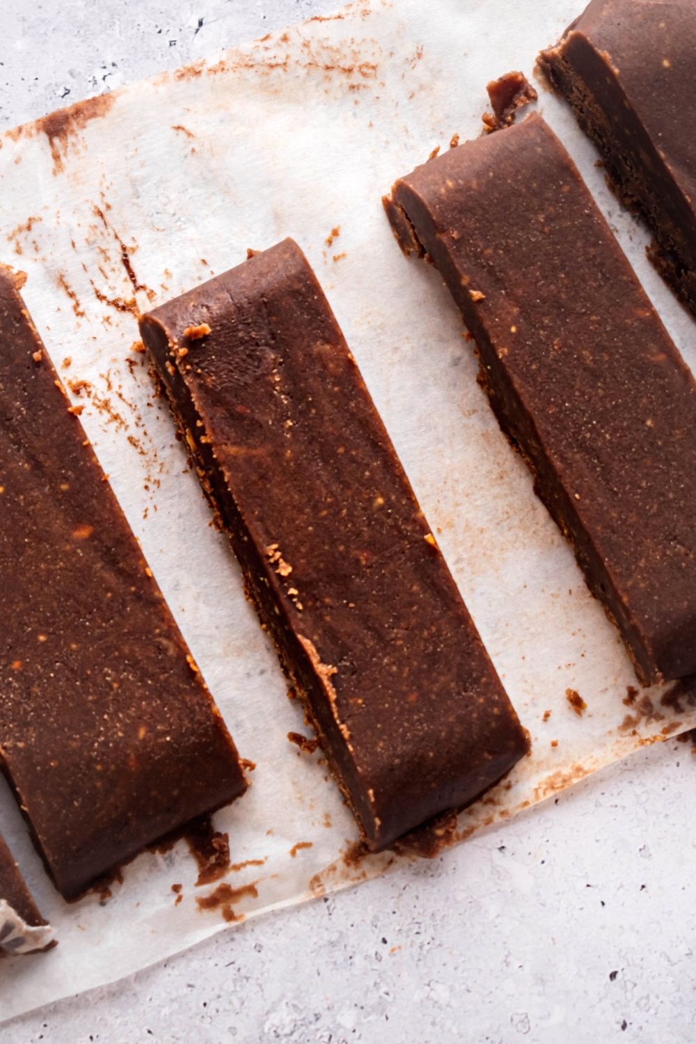 A couple of strips of chocolate peanut butter fudge on parchment paper on a white counter.