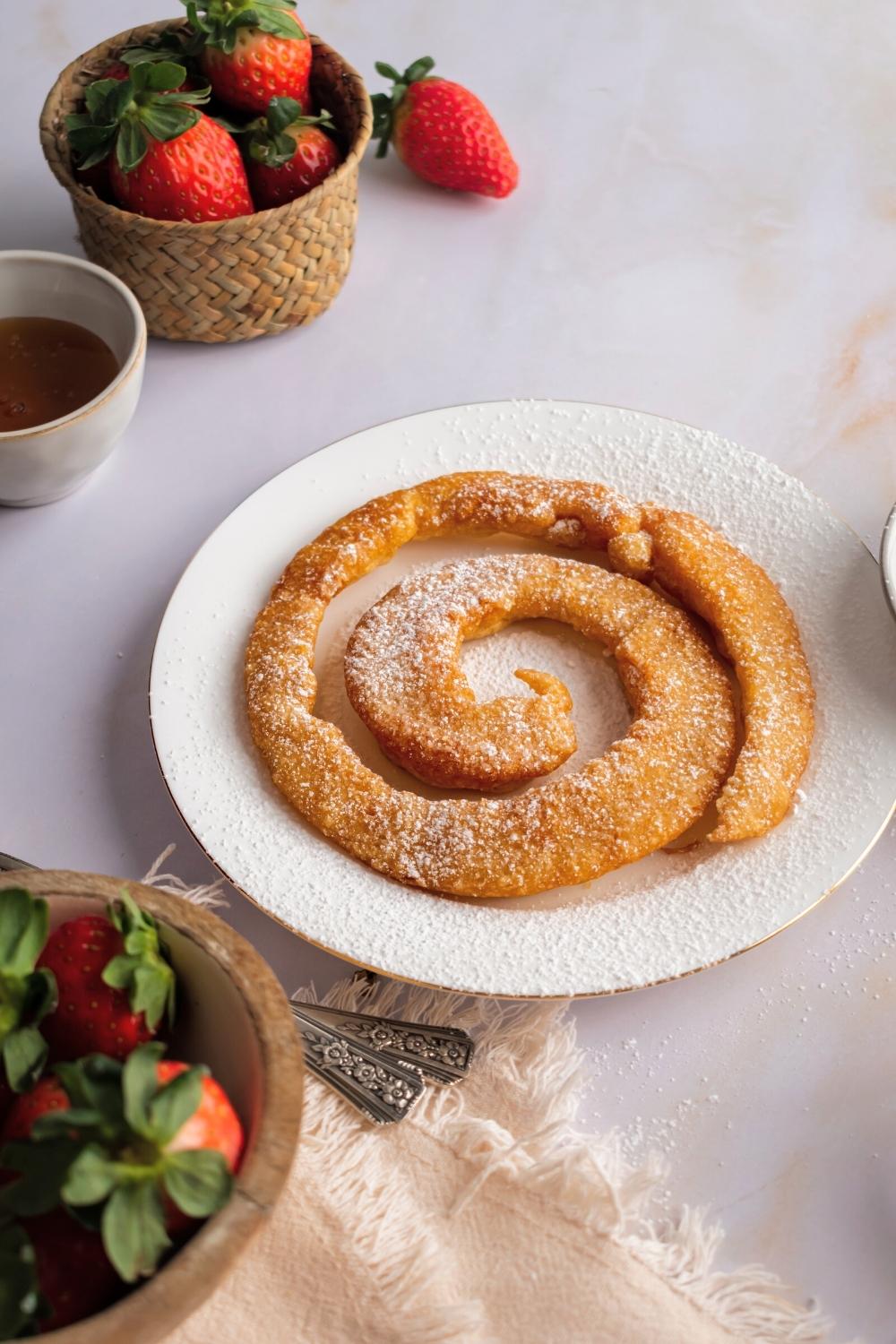 A funnel cake made with pancake mix that is on a white plate on a white counter.