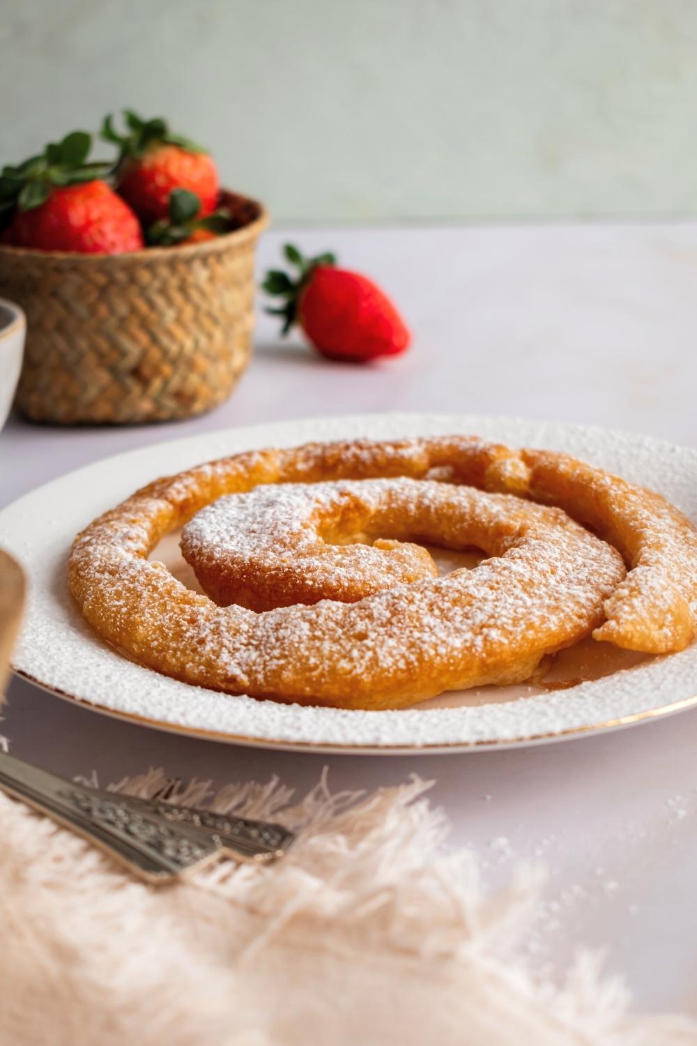 A funnel cake with pancake mix that is on a white plate on a white counter.