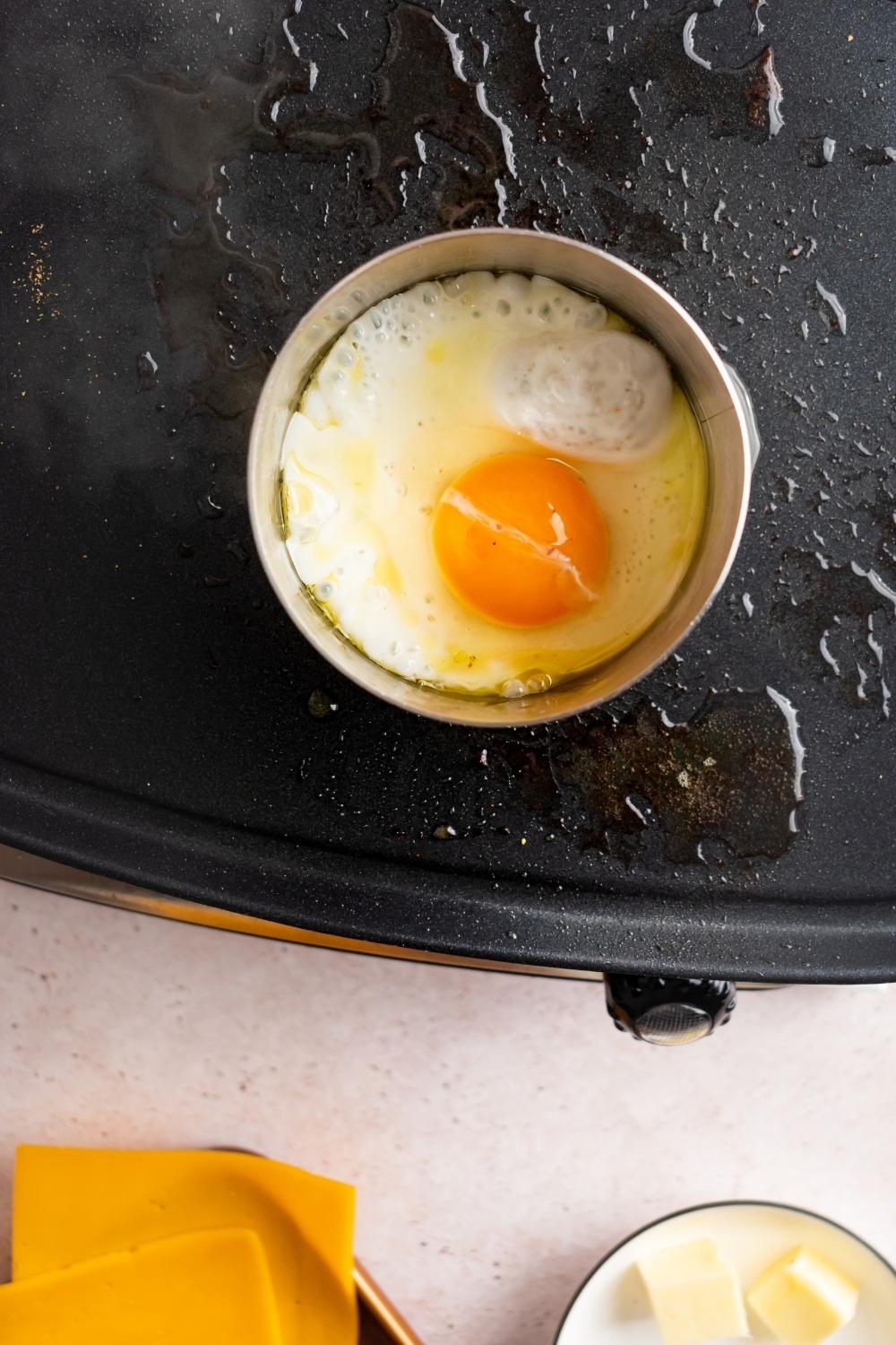 An egg in a round mold on a griddle.