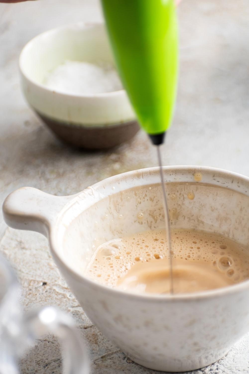 Any immersion blender mixing caramel cold foam in a cup.