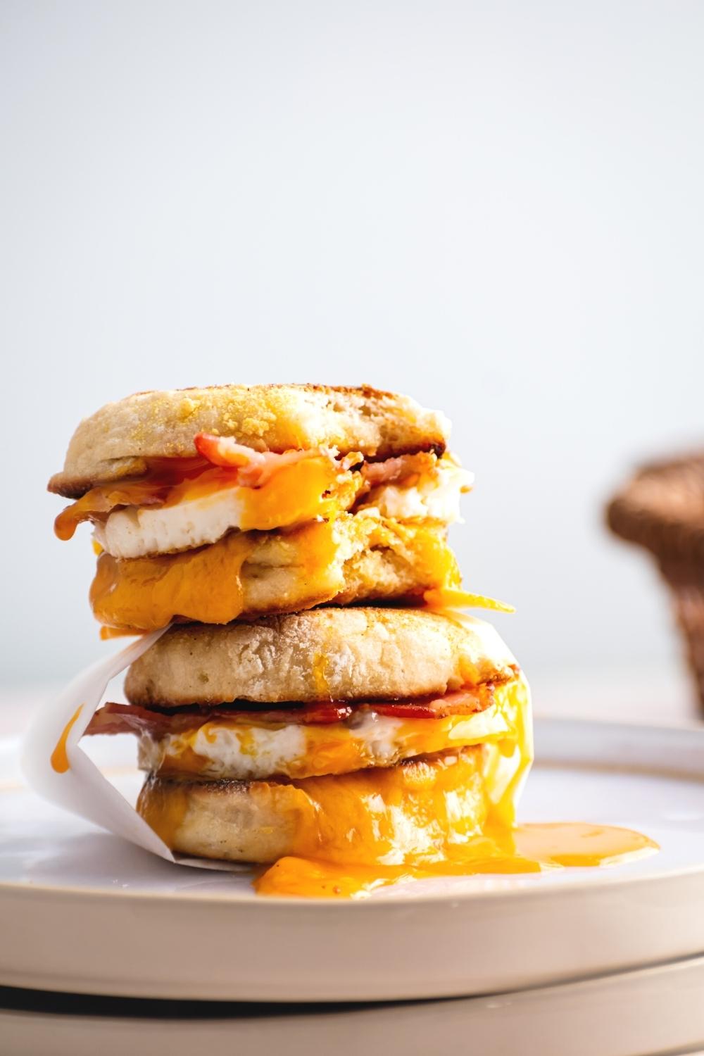 Two egg mcmuffins stacked on top of one another on a white plate.