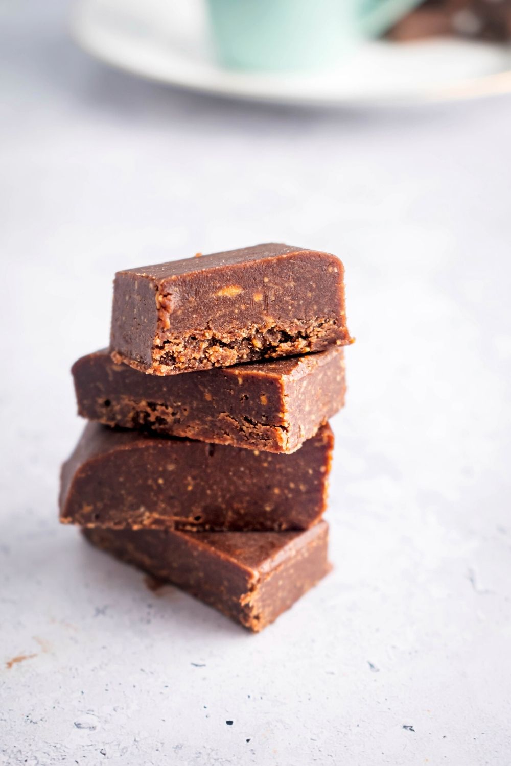 Four pieces of two ingredient fudge stacked on top of one another on a white counter.