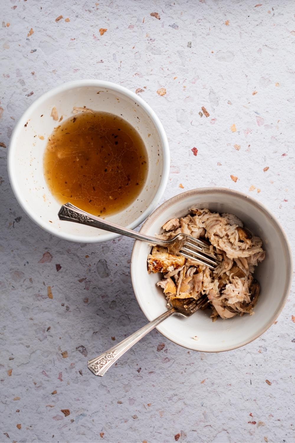 A bowl of rotisserie chicken and a bowl of the chicken juice on a white counter.