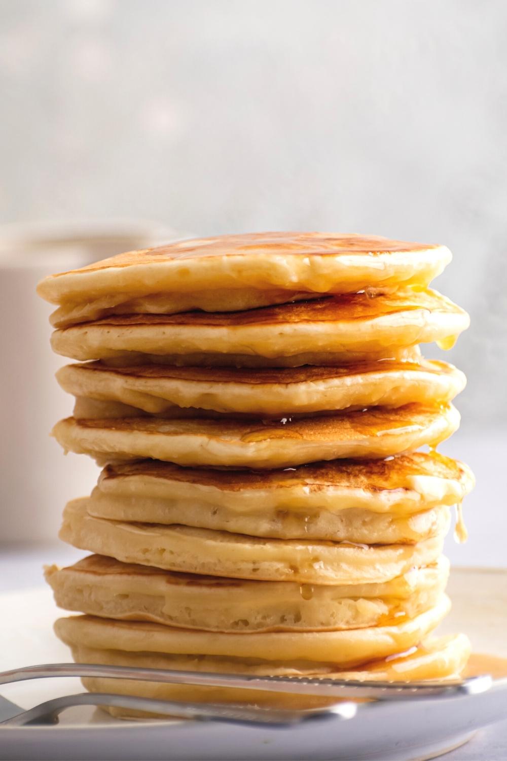 A stack of a bunch of pancakes with maple syrup dripping down the sides of them.