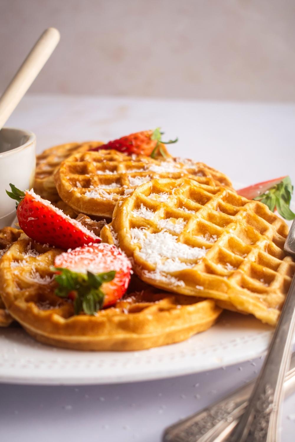 A couple of waffles on top of one another on part of white plate.