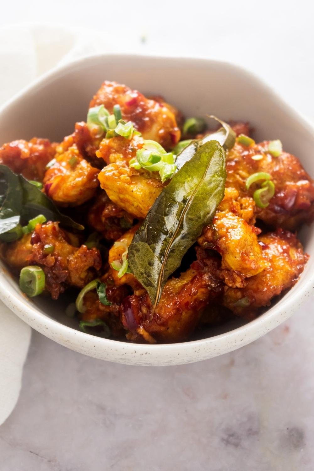 Chicken 65 in a white bowl on top of the white counter.