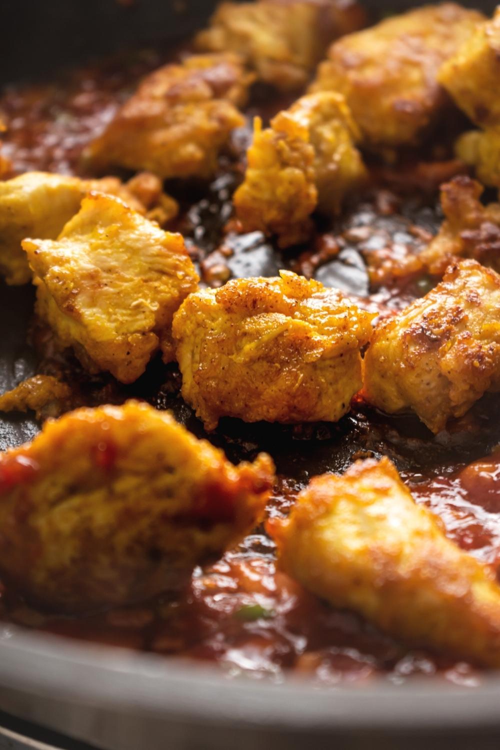 Chicken 65 frying in a black skillet.