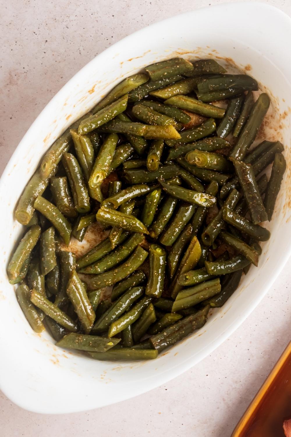 Seasoned green beans in a white casserole dish.