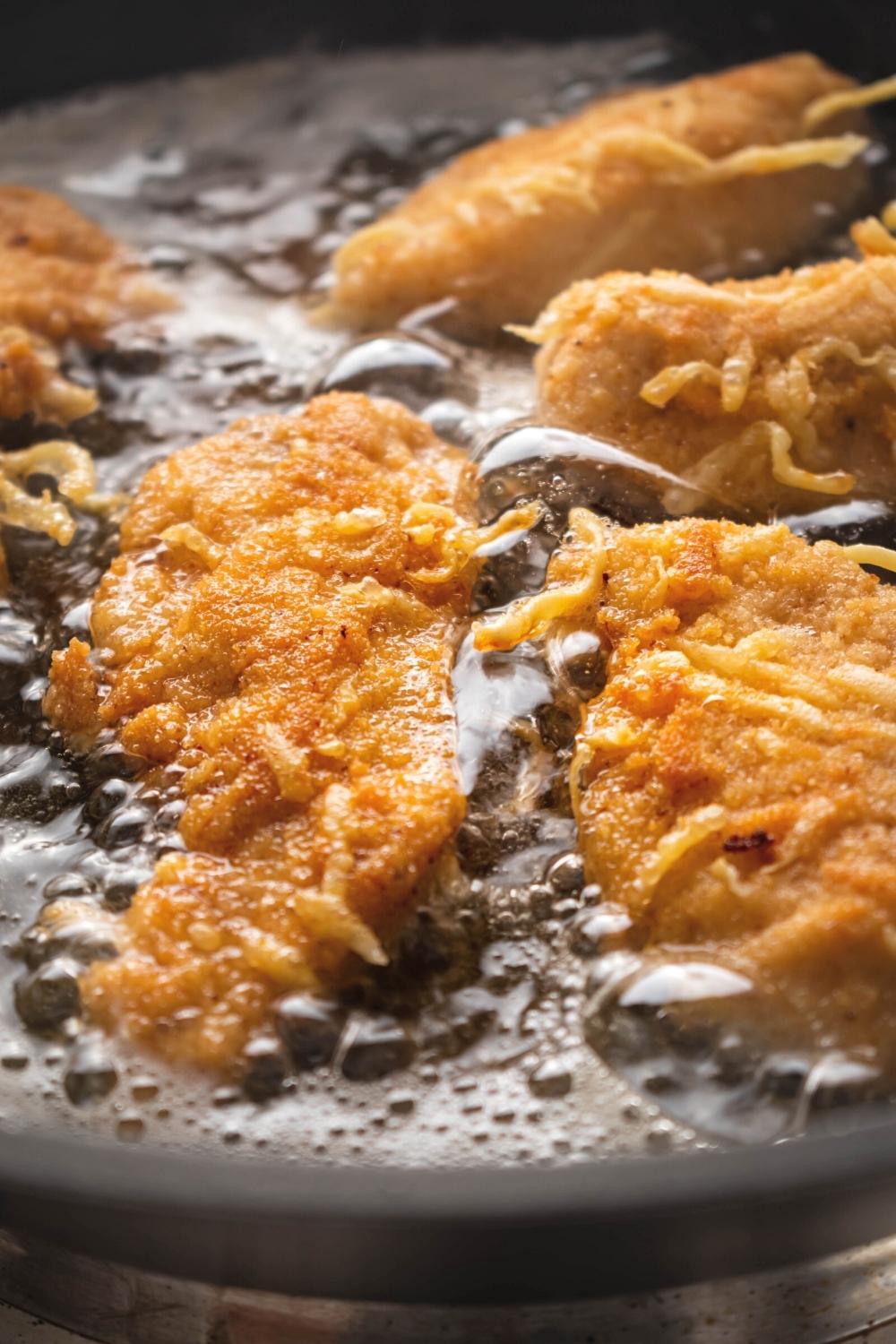 Crispy chicken fritta in a pan of oil.