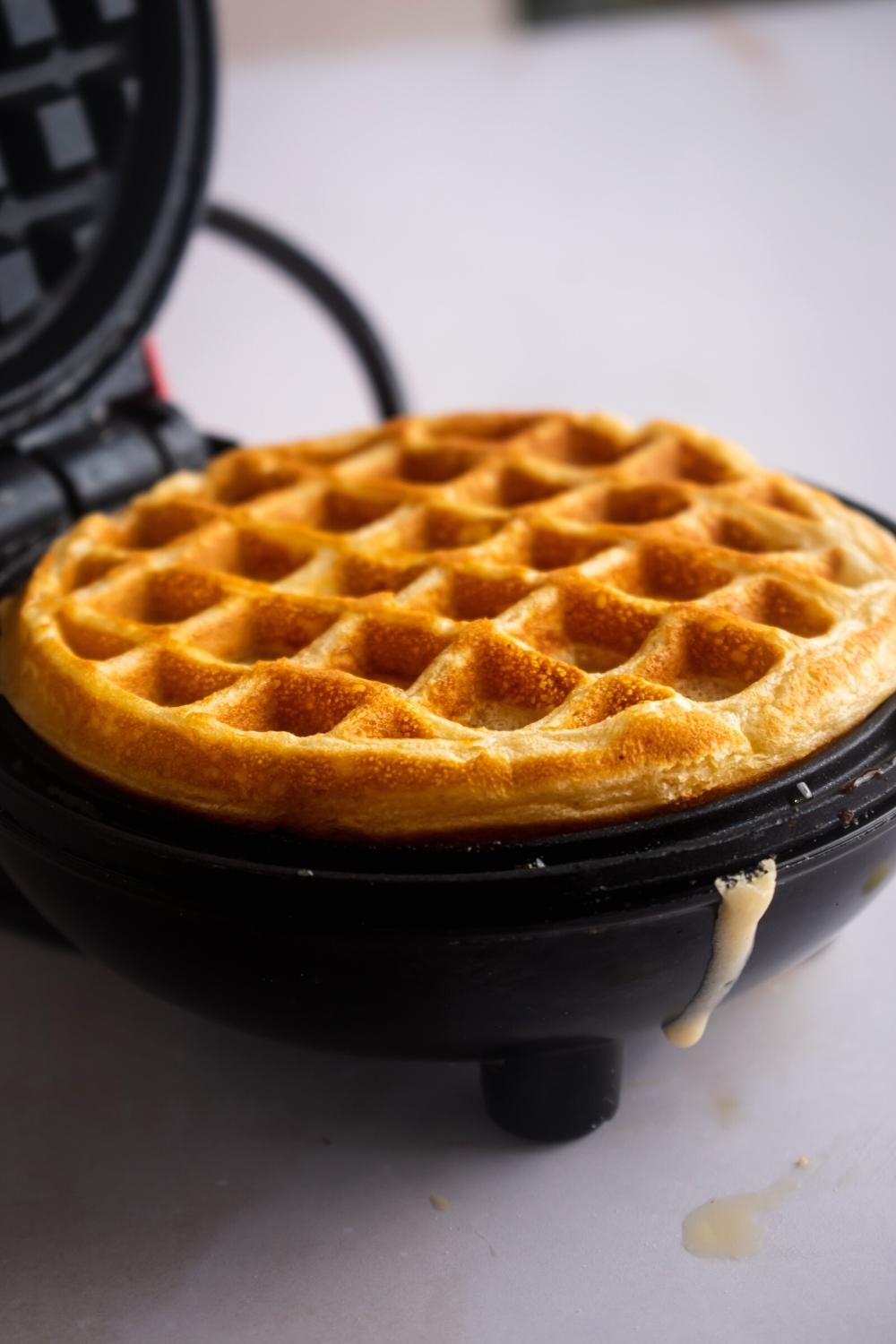 A cooked waffles in a waffle iron.