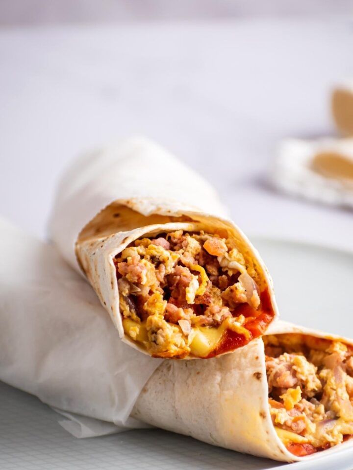 A breakfast burrito on top of another McDonald's breakfast burrito on a plate.
