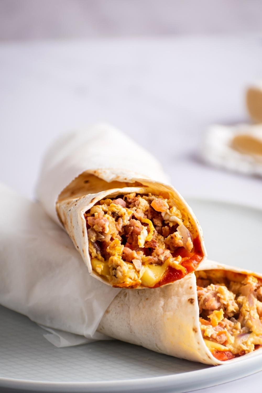 A breakfast burrito on top of another McDonald's breakfast burrito on a plate.