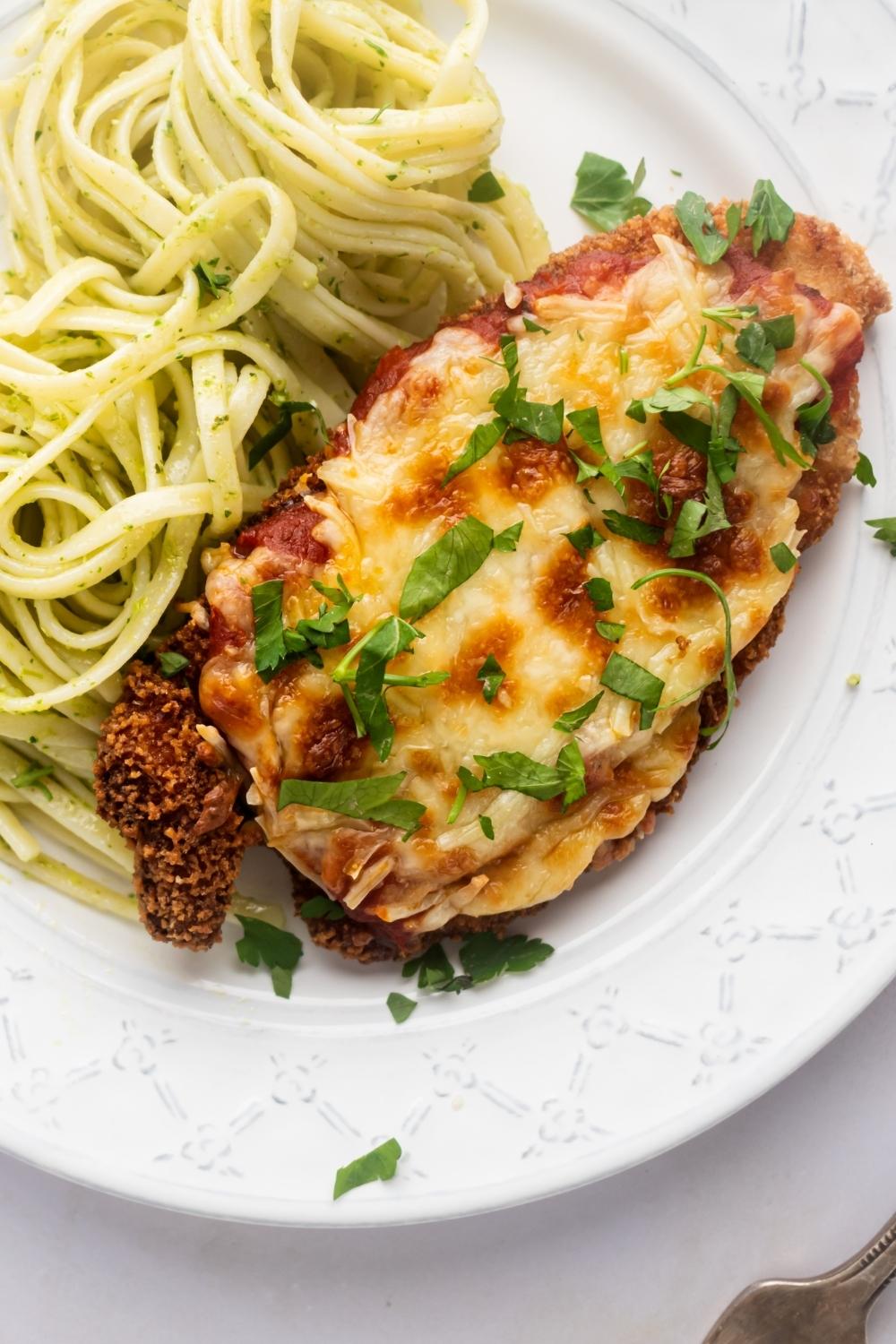 A piece of chicken Parm and some spaghetti and part of a white plate.