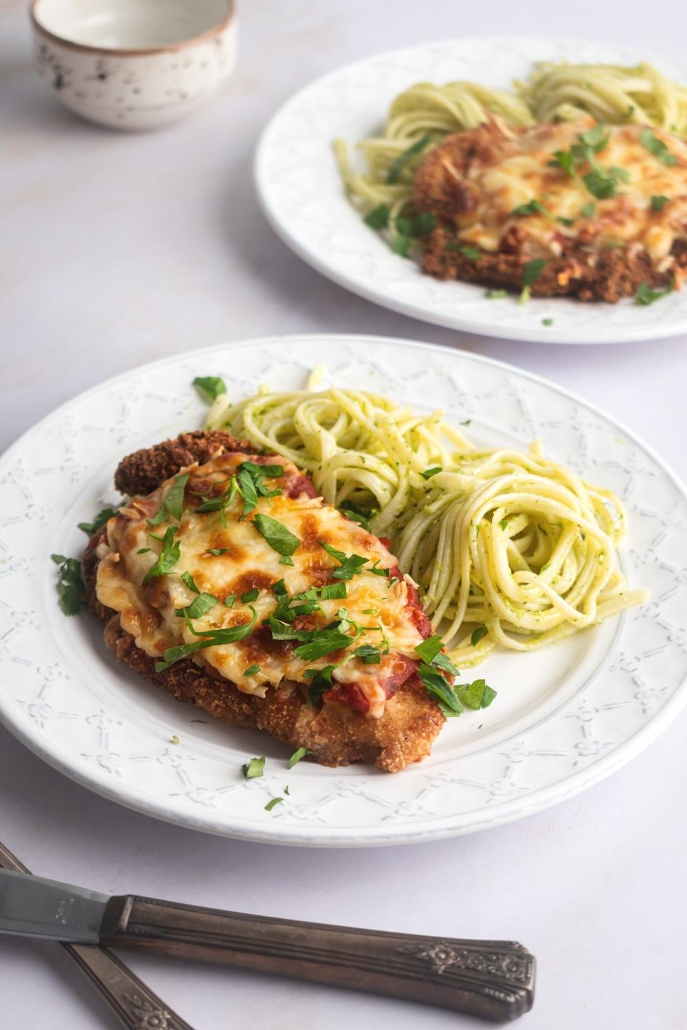 A piece of chicken Parmesan and spaghetti on a white plate.