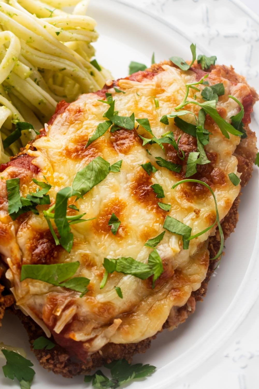 A piece of chicken parm on part of a white plate.