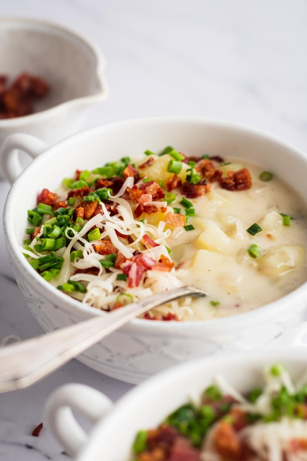 White bowl filled with outback baked potato soup with a spoon in it.
