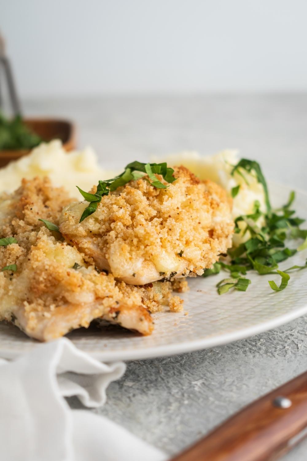 Two pieces of parmesan crusted chicken on a white plate.