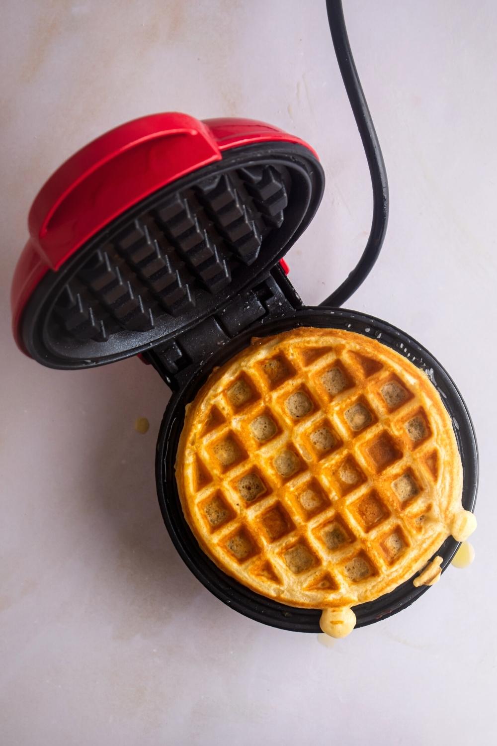 Open waffle iron with a clot waffle in it.