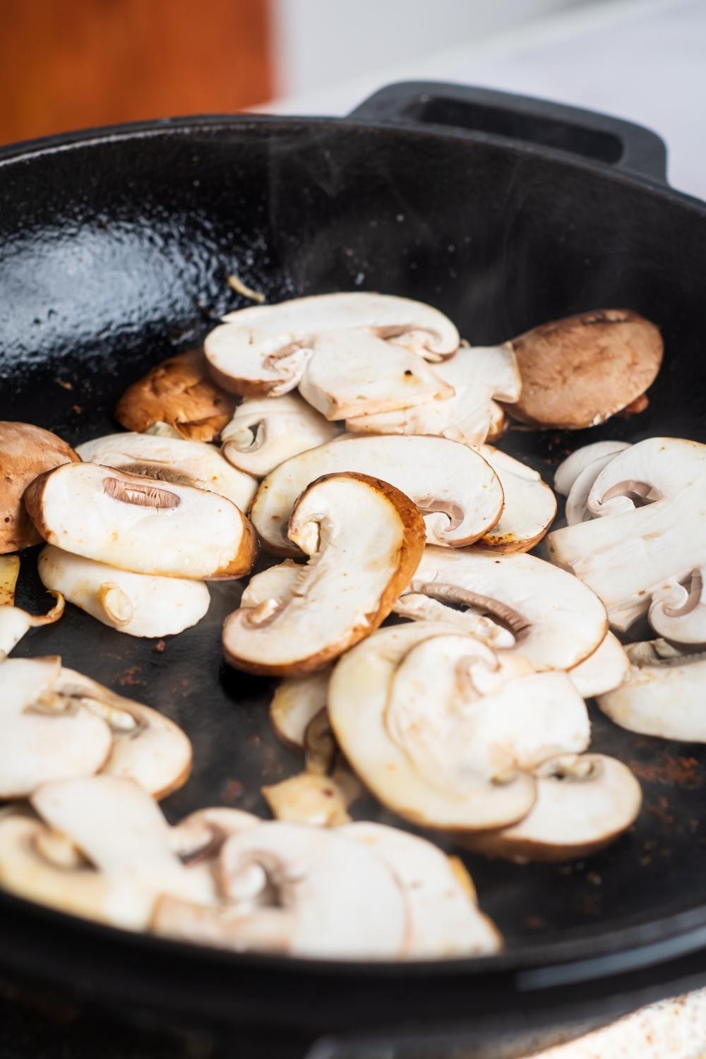 A skillet with uncooked mushrooms.
