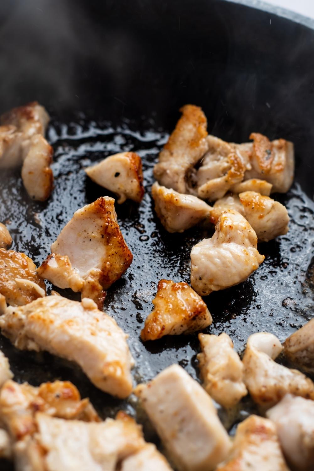 A skillet with golden brown cubed chicken.