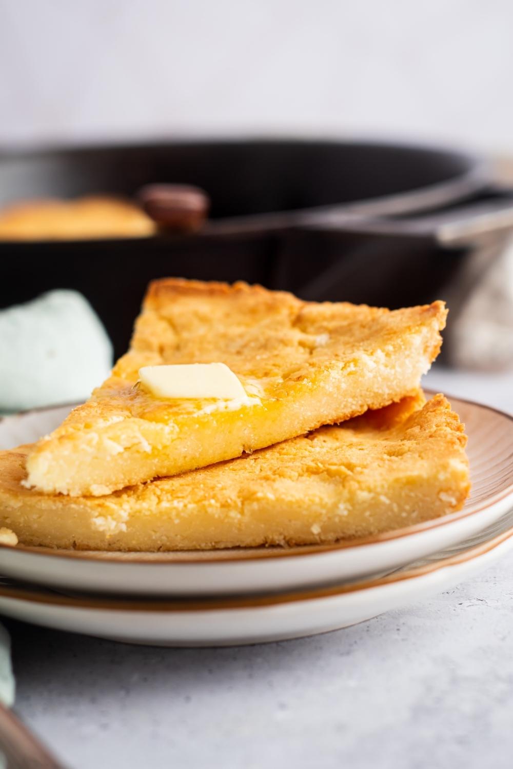 A triangle of corn bread on top of another triangle cornbread on to white plates.
