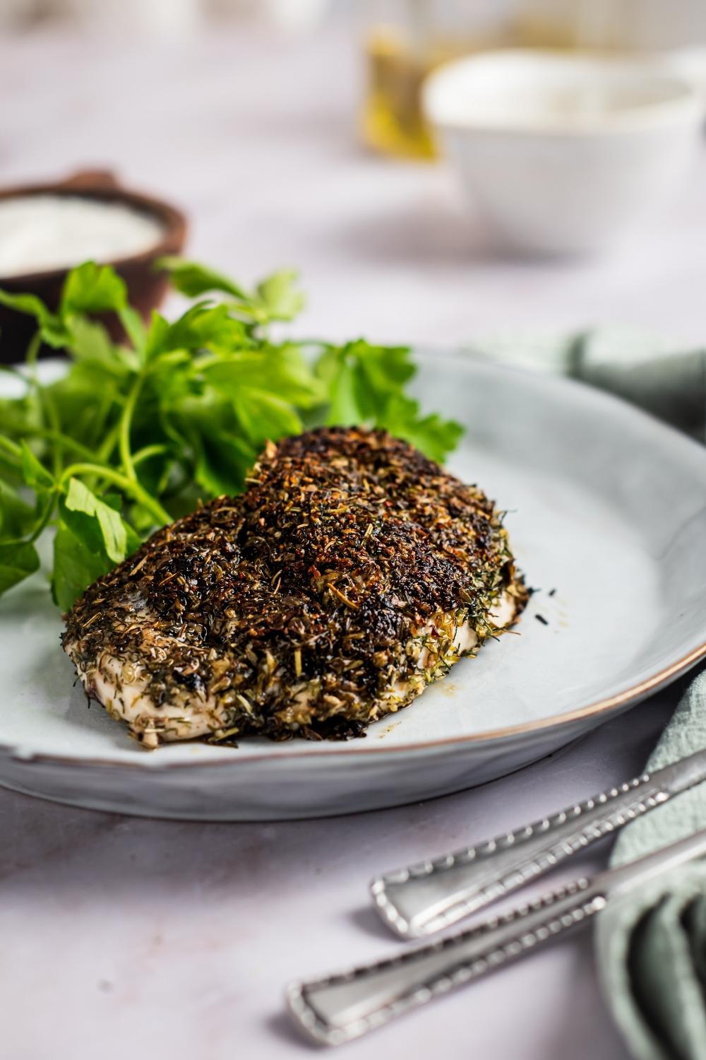 A piece of herb crusted chicken that is on a plate.