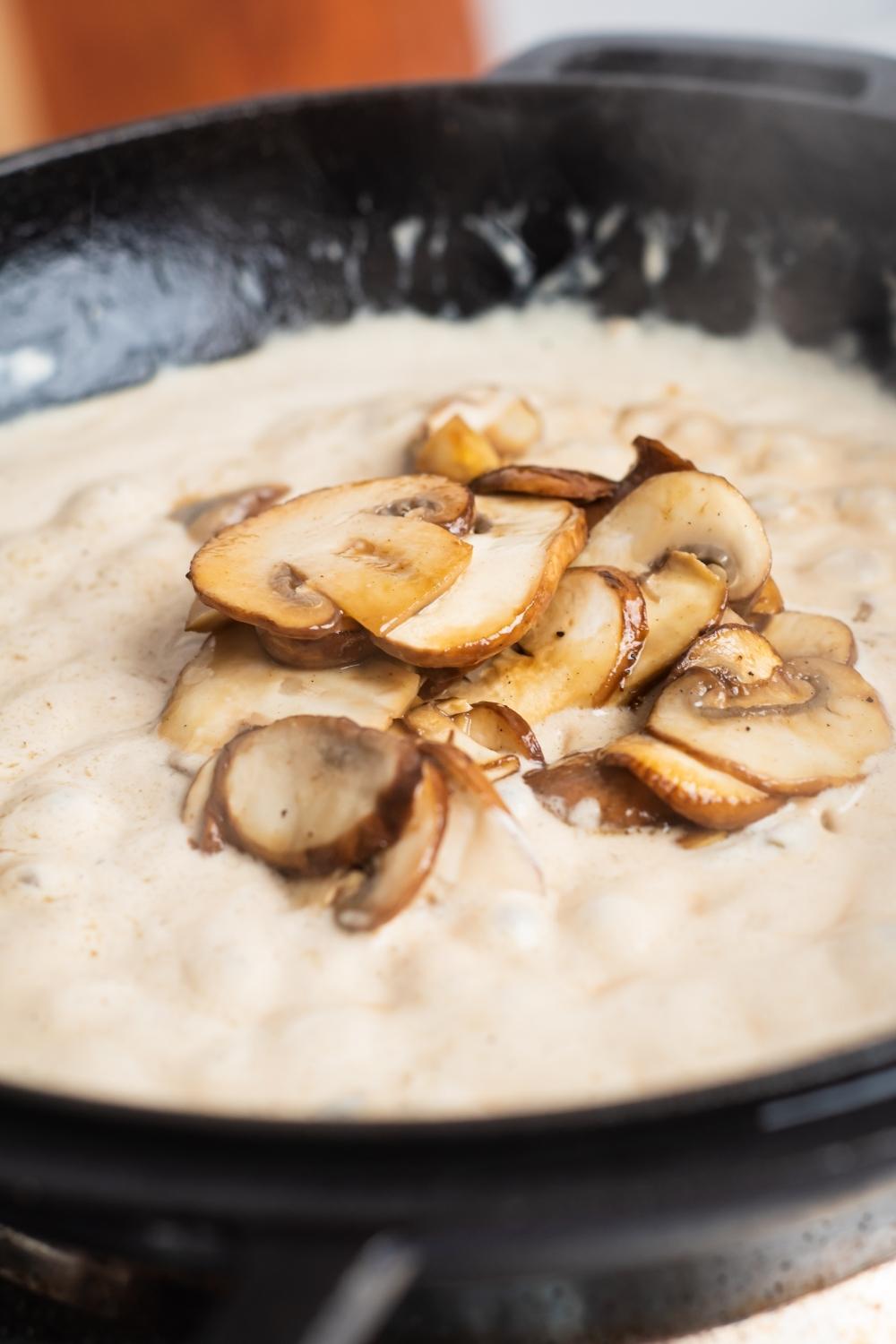 A skillet with creamy sauce and cooked mushrooms in the center.