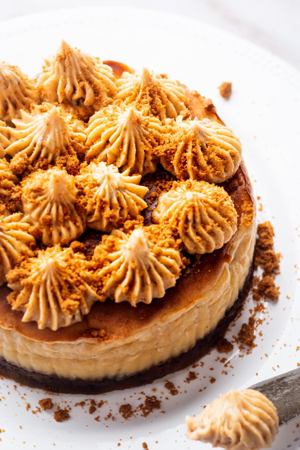 A close up of Biscoff cheesecake with dolloped frosting on top sprinkled with crumbled lotus Biscoff cookies.