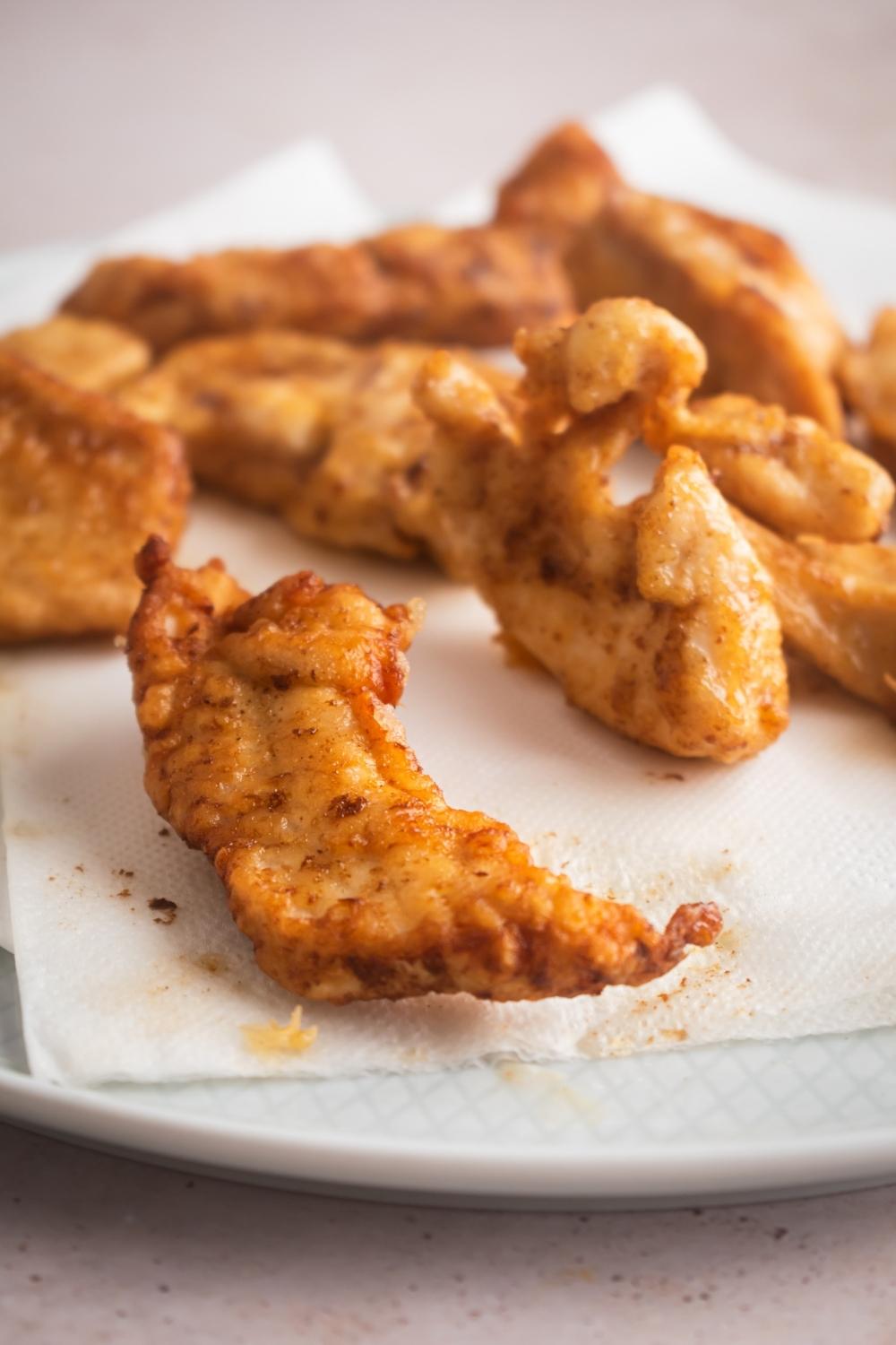 A close-up of cooked Mar Far chicken chunks laying on a paper towel lined plate.