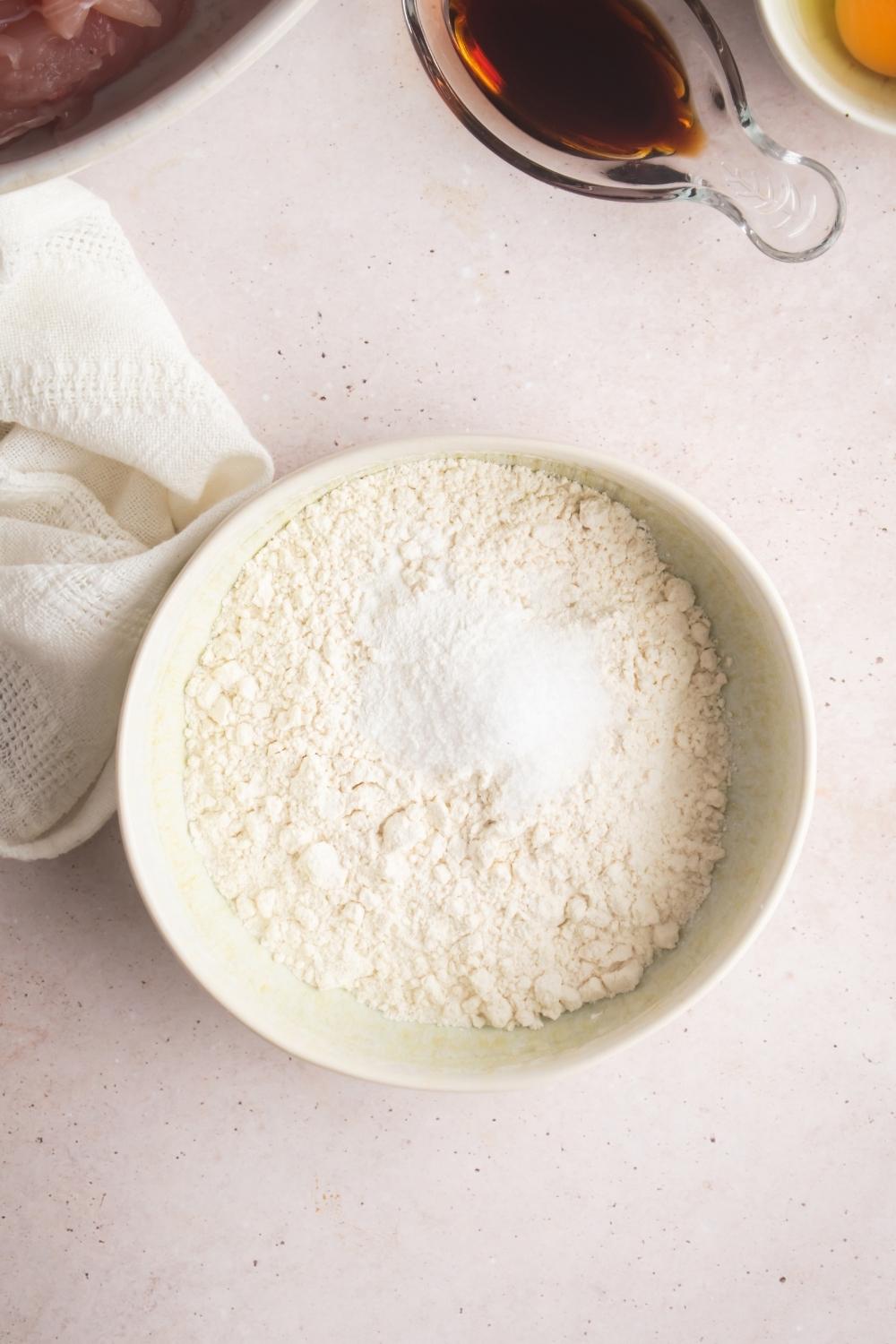 An overhead view of flour being mixed with baking powder and salt.