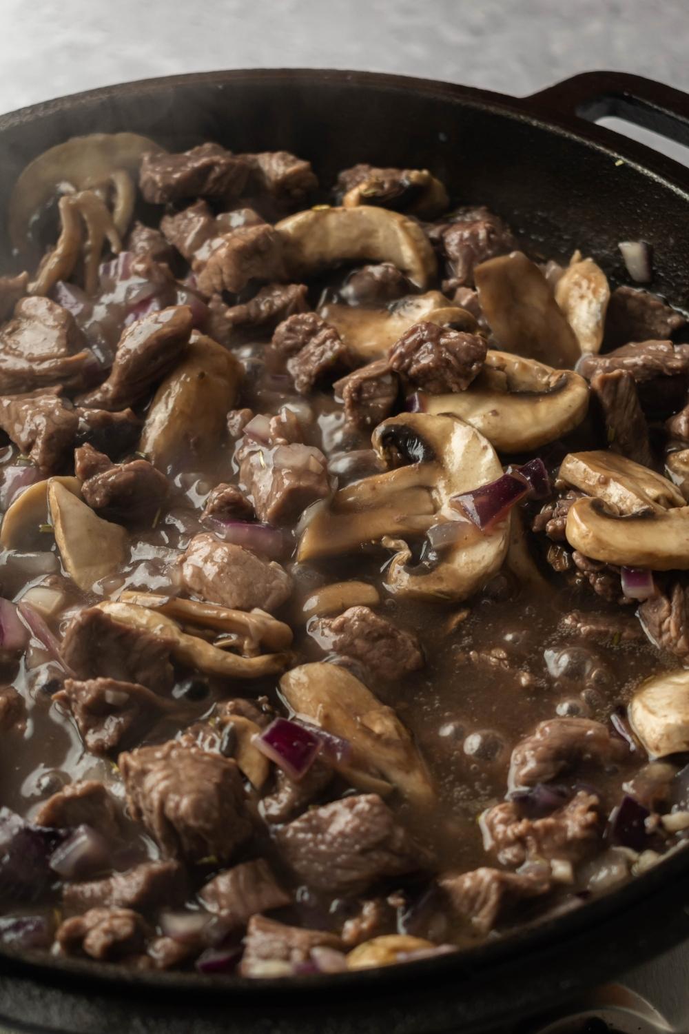 A close up of Beef pot pie filling in an iron pot.