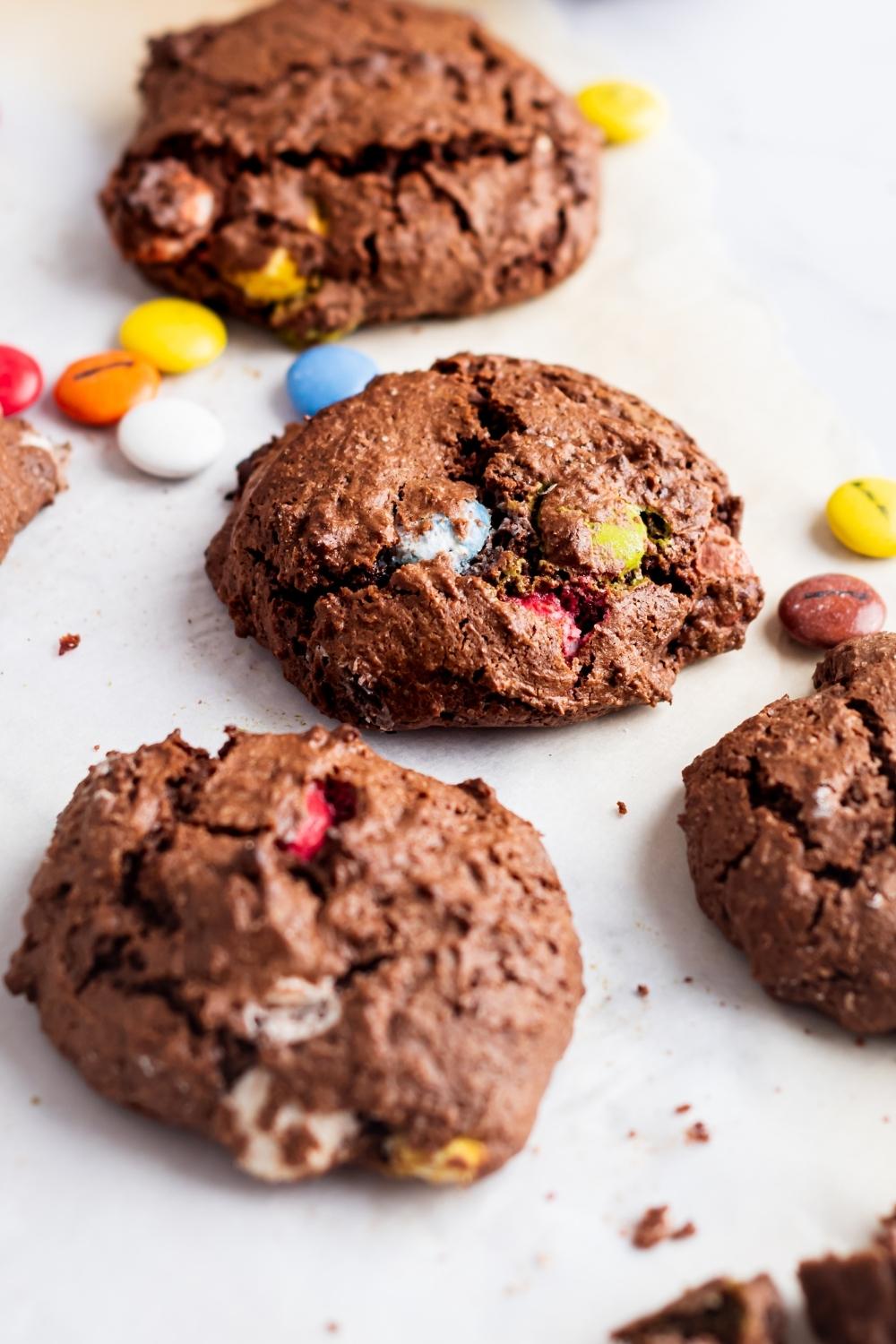 Four chocolate cake mix cookies on a piece of parchment paper.