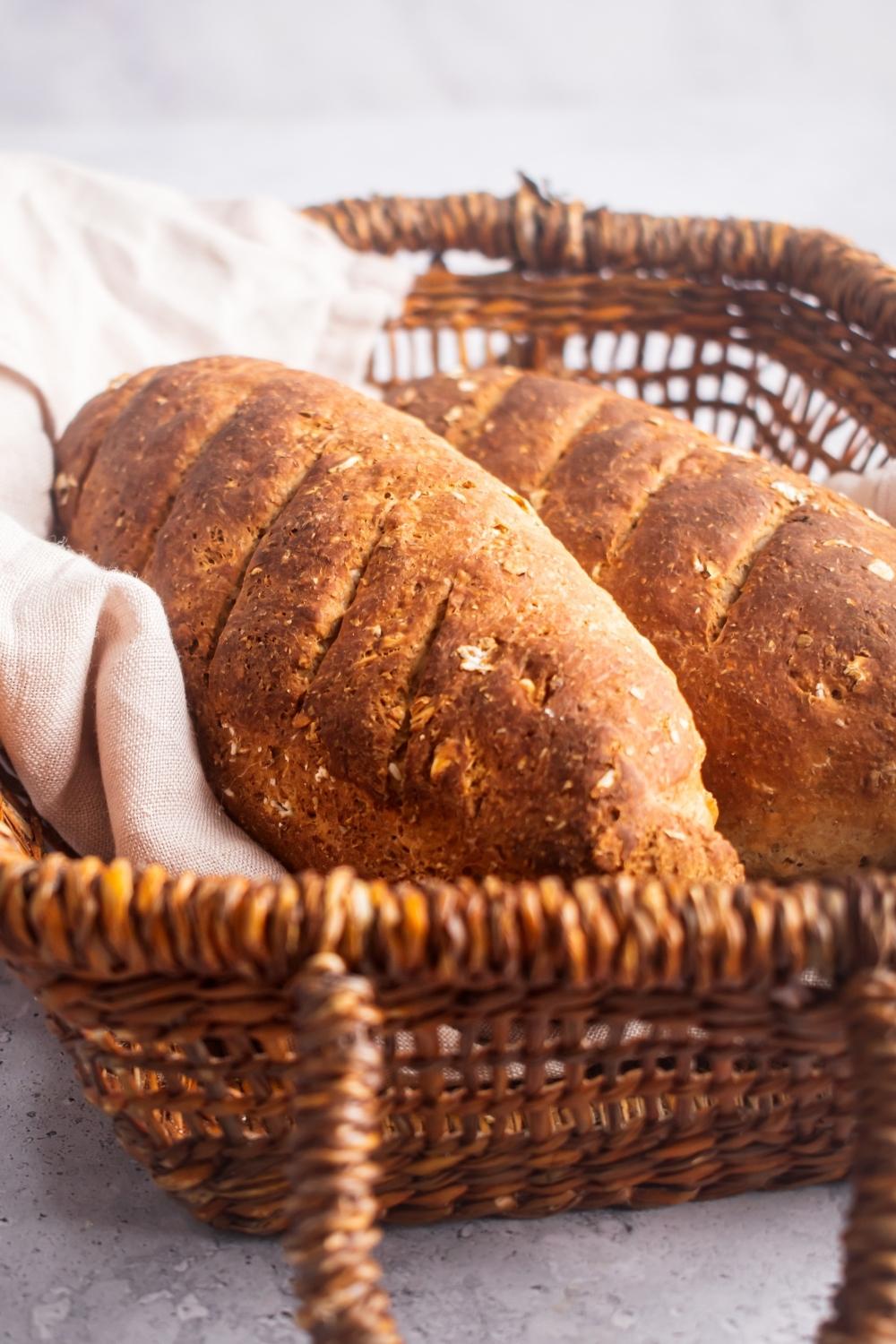 A close-up of two loaves of bread in a basket with a kitchen towel lining it.
