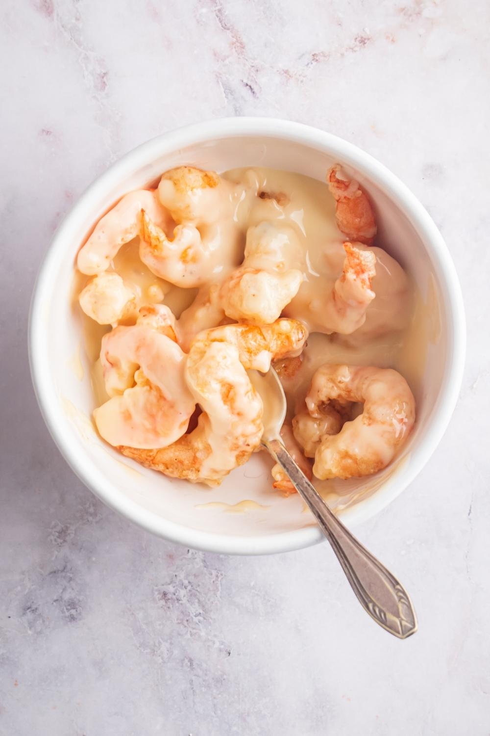 A bunch of shrimp covered in a honey sauce in a white bowl.