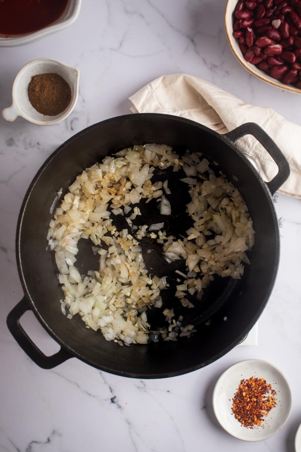 An overhead view of a skillet cooking garlic and onion.