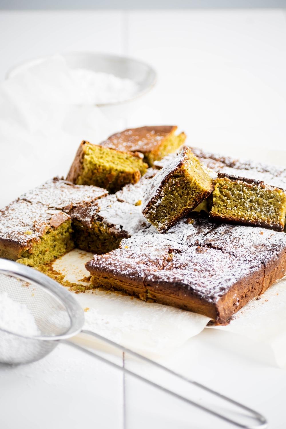 A bunch of squares of matcha brownies on a white counter.