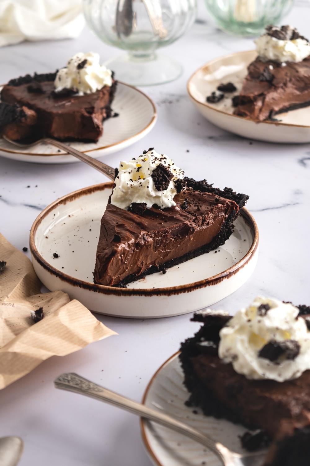 A bunch of white plates with slices of mud pie on them.