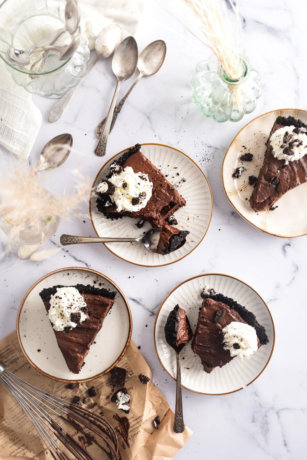 Four slices of mud pie on white plate on top of a white counter.