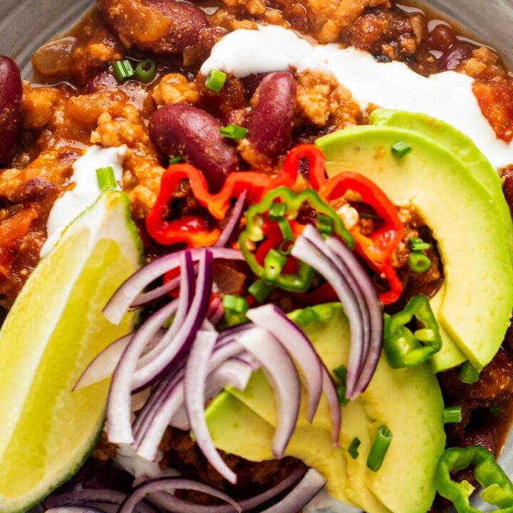 Avocado and red onion on top of a bowl of Texas chili.