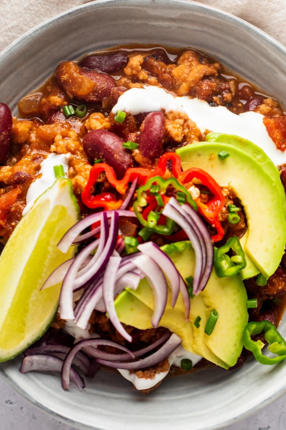 Avocado and red onion on top of a bowl of Texas chili.