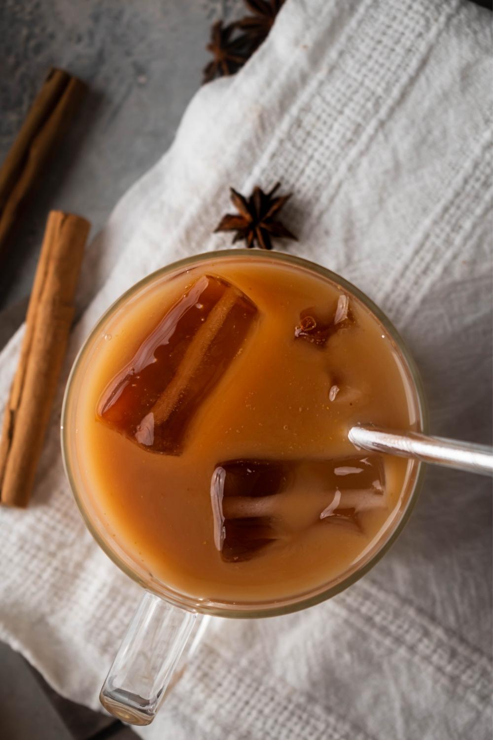 A glass filled with thai tea with a straw submerged in it.