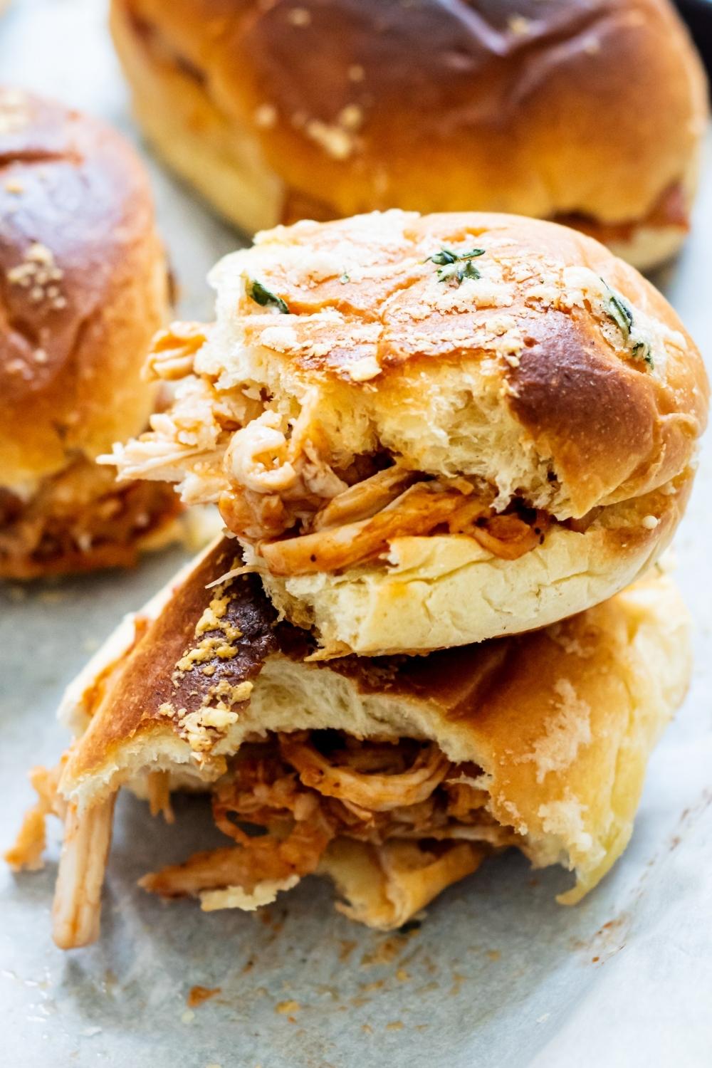 A close-up of a barbecue chicken slider that has been cut in half to reveal the barbecue chicken between the roll.