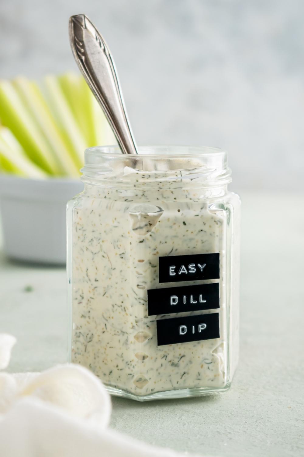 A mason jar containing homemade dill dip with a spoon in it.