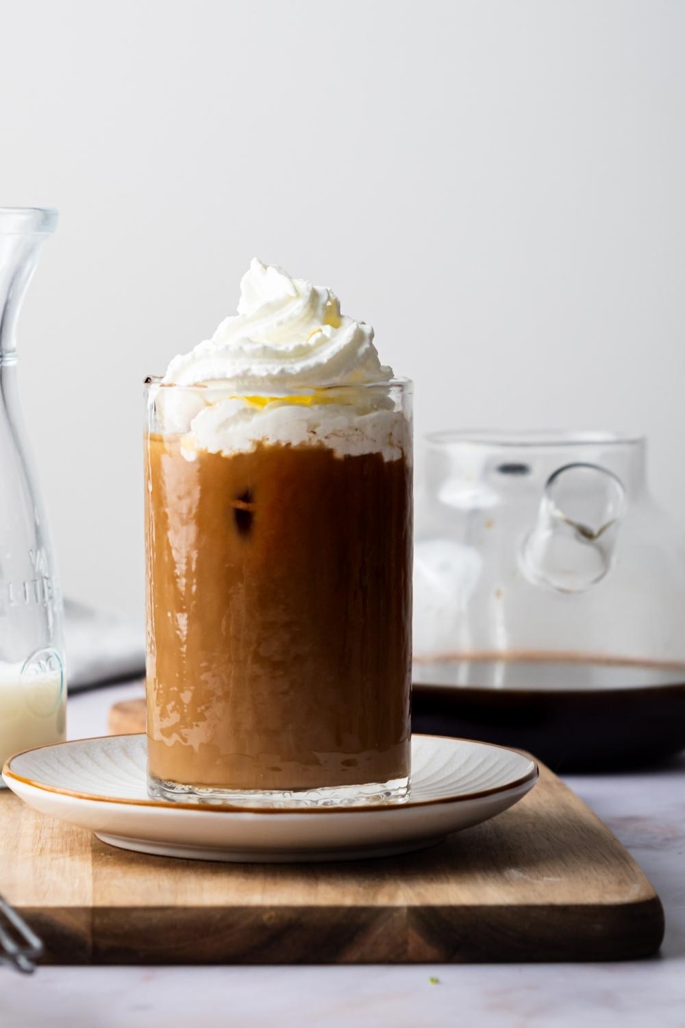 A side view of homemade McDonald's iced coffee topped with whipped cream in a glass.
